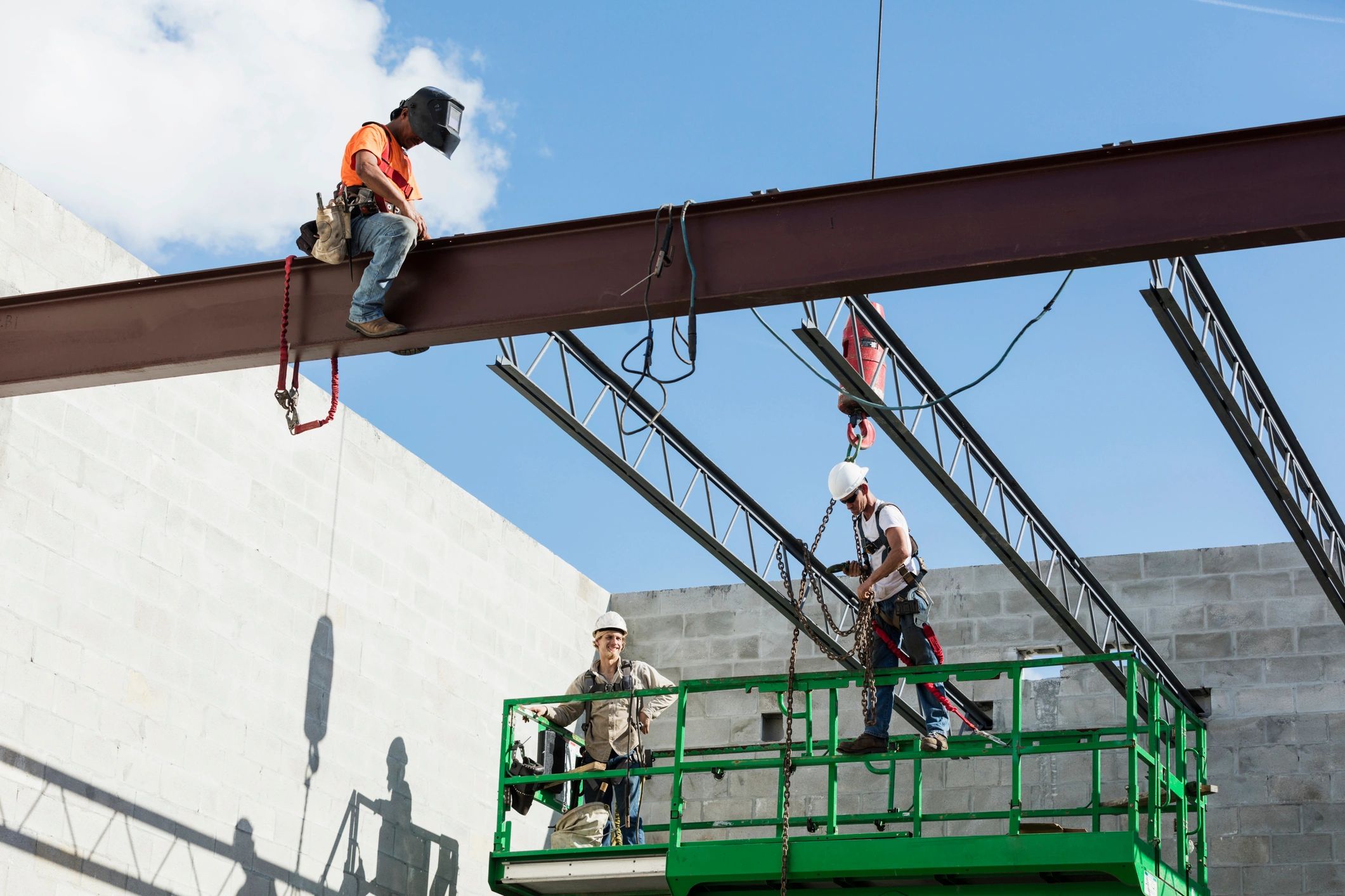 Crew installing steel roof joists at a construction site