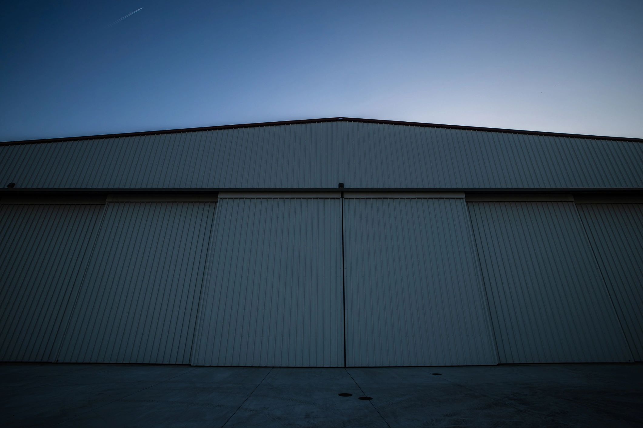 Wide exterior view of an aircraft hangar at sunset