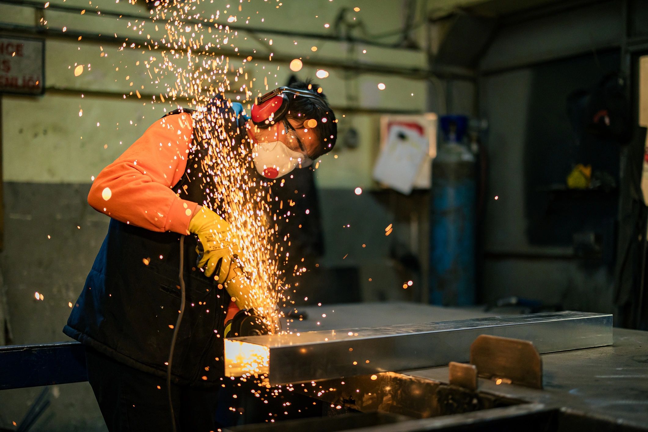 Metalworker using an angle grinder with sparks in a fabrication shop
