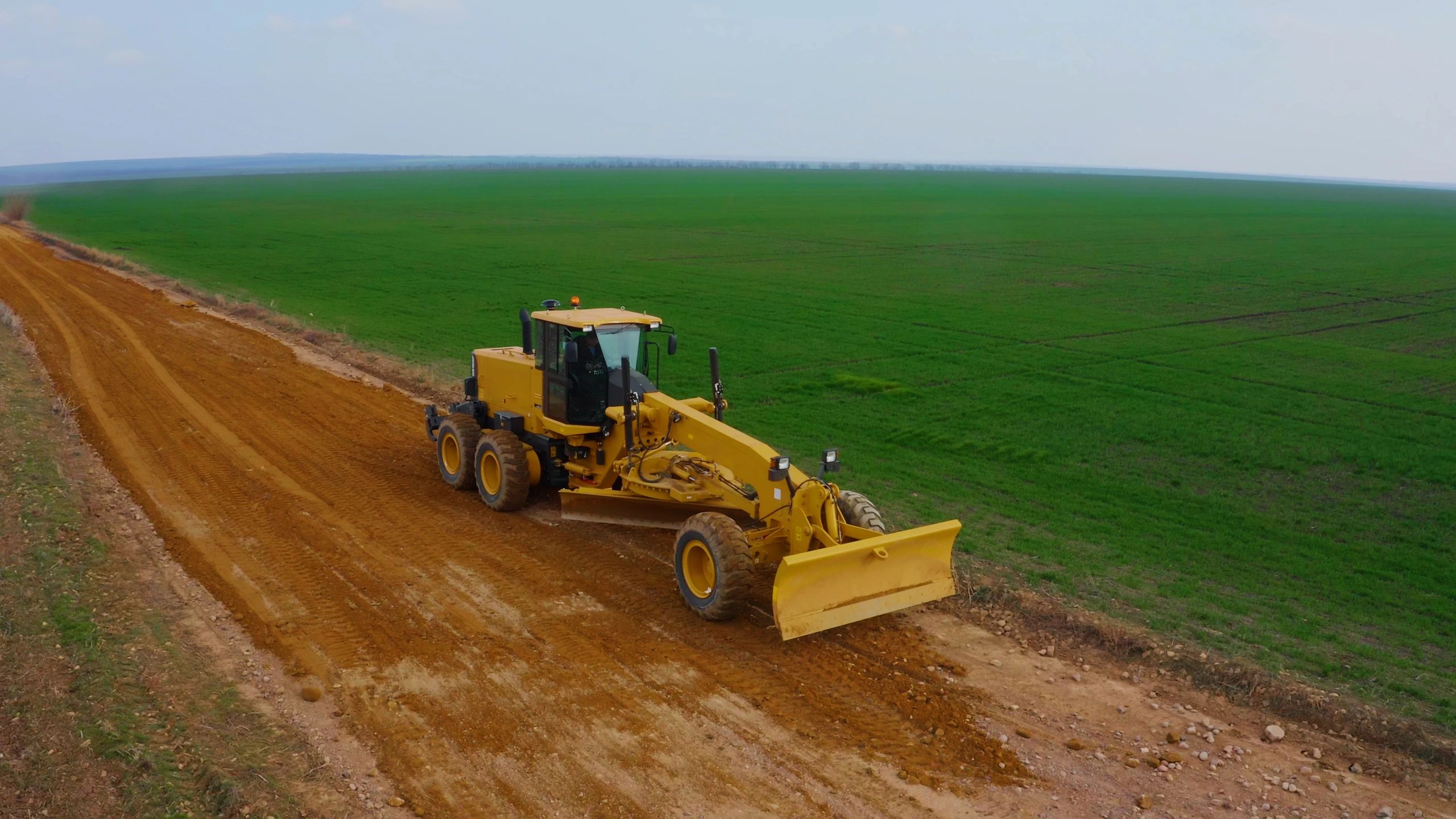 Motor grader shaping a rural dirt road base