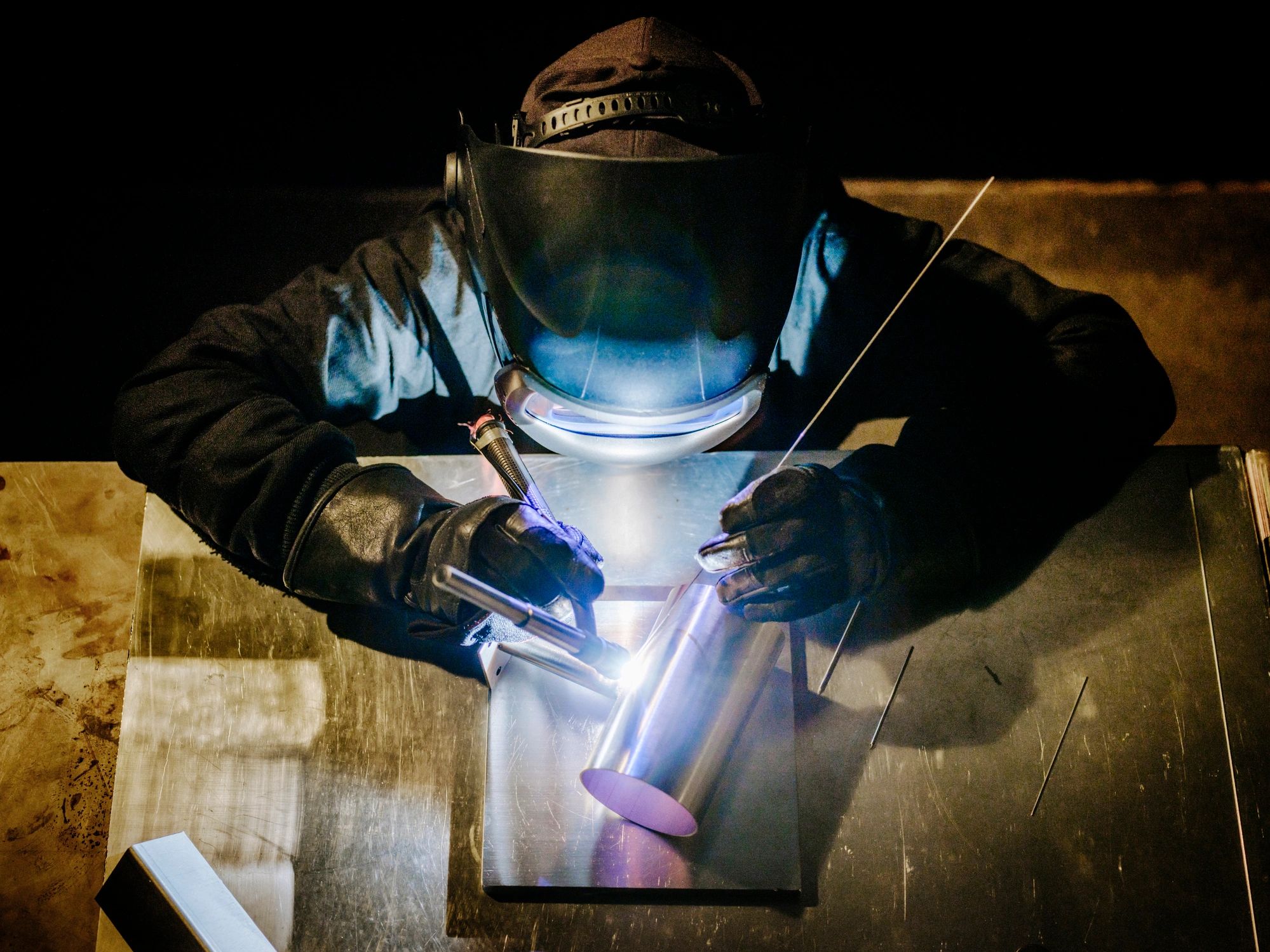 TIG welder working on a metal component in a workshop